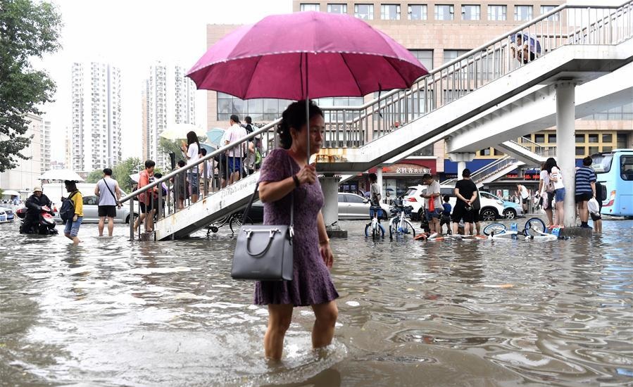 A woman wades through a flooded street in Hedong District of Tianjin