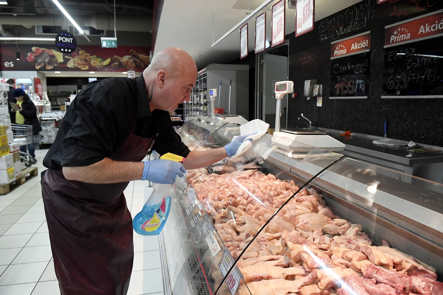 An employee disinfects the glass over of a butcher counter to prevent the spread of the novel coronavirus in a food store in Budapest Hungary