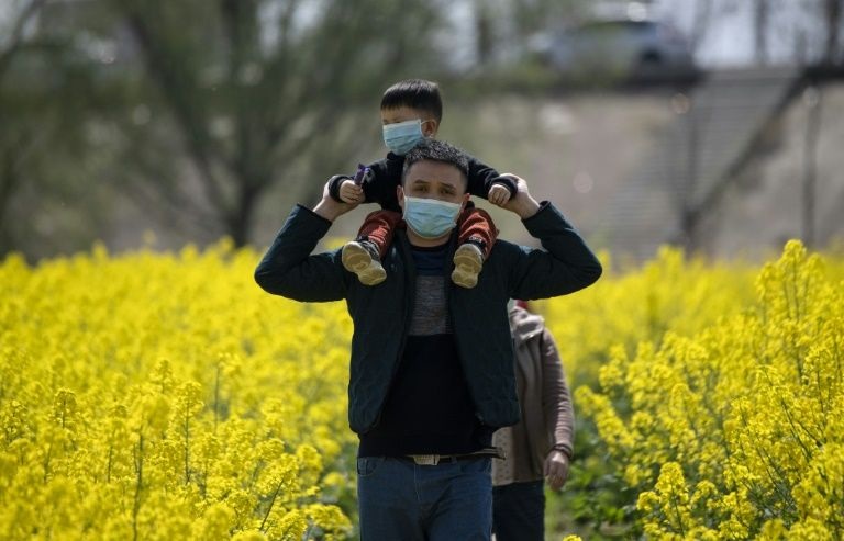 People wearing face masks walk through a rapeseed farm used to produce canola oil in Chinas central Jiangxi province that borders Hubei province