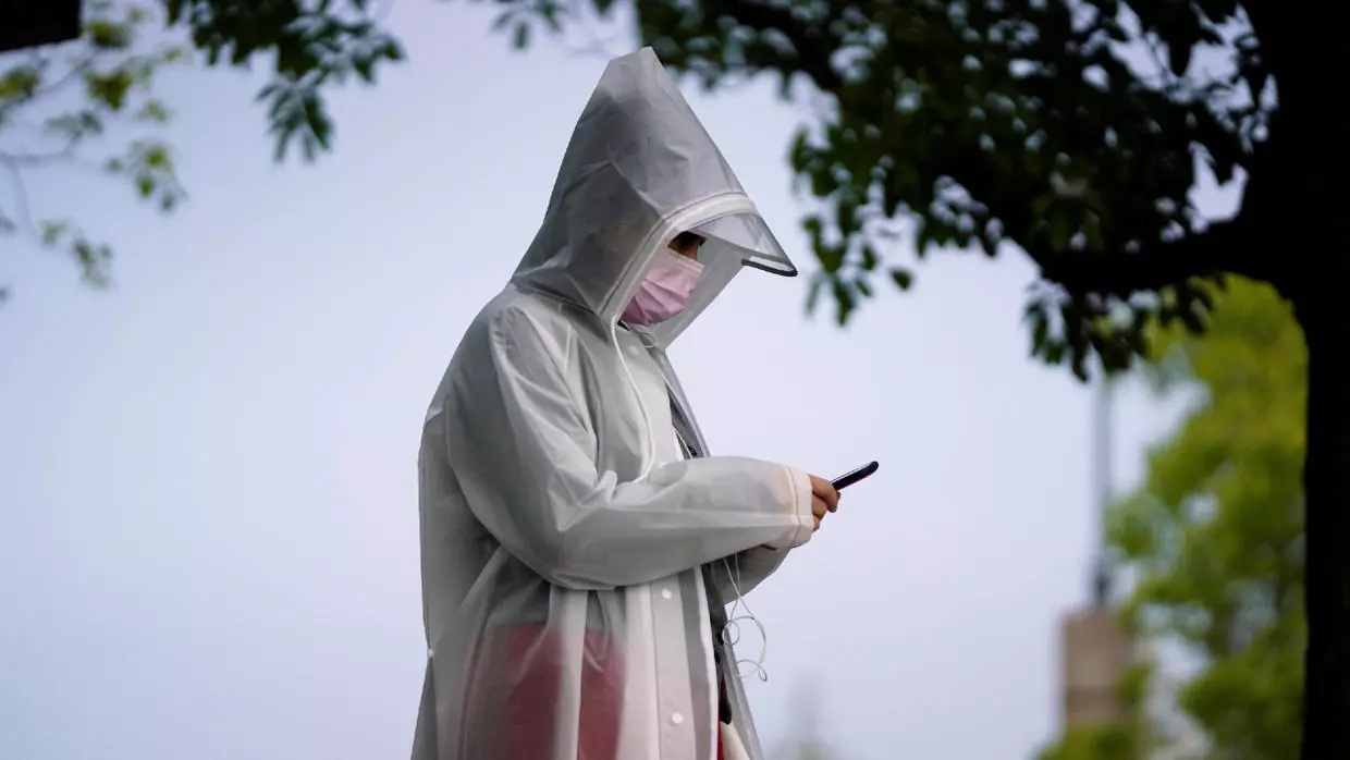A resident wearing protective gear checks a mobile phone in Wuhan Hubei province as China holds a national mourning day for those who died of the coronavirus disease COVID 19 on the Qingming tomb sweeping festival