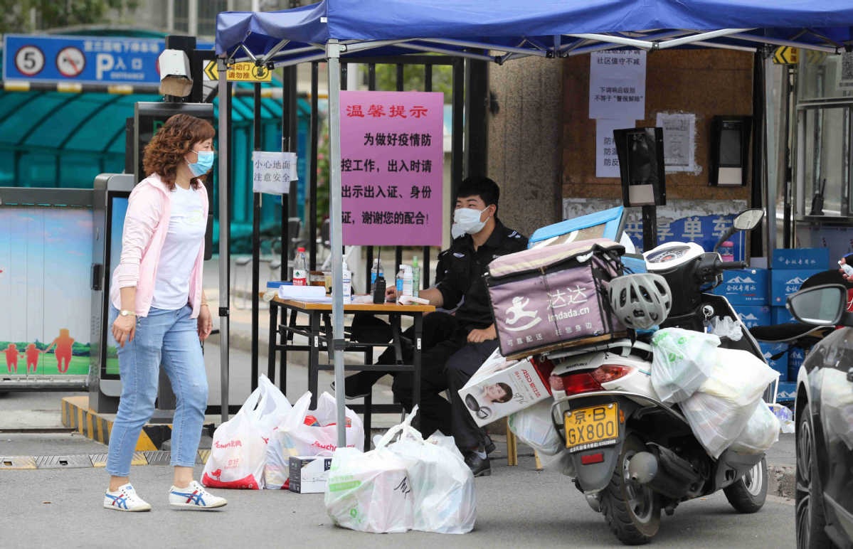 A resident comes out to collect daily necessities in a community near Xinfadi in Fengtai district Beijing