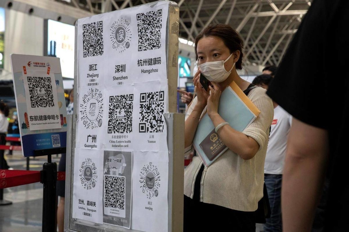 A passenger looks at a board with QR codes for health screening from different provinces at the Beijing Capital Airport terminal 2 in Beijing